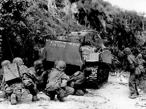 Marines take cover behind a M4 Sherman tank while clearing out the northern end of Saipan, 8 July 1944.